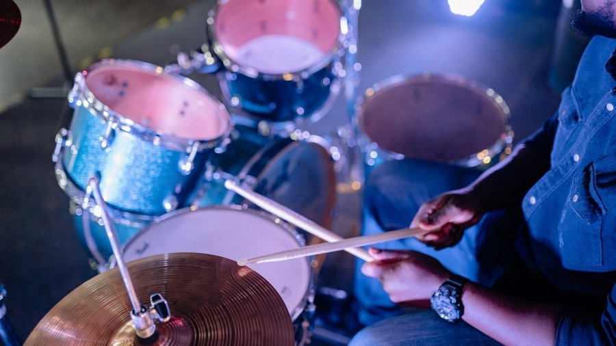 Blue drum kit being played with drum sticks