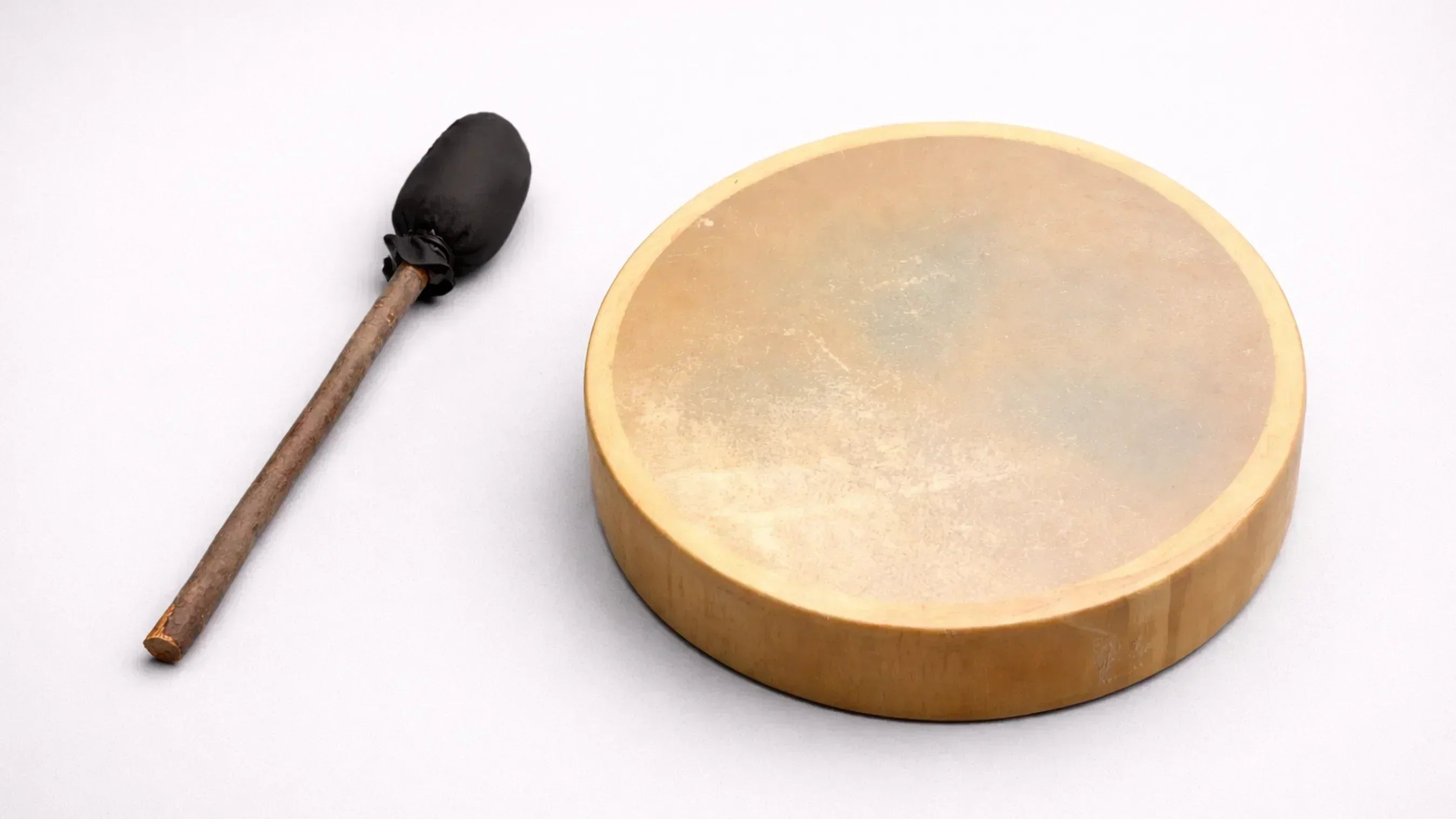 grey background shamanic drum with black beater