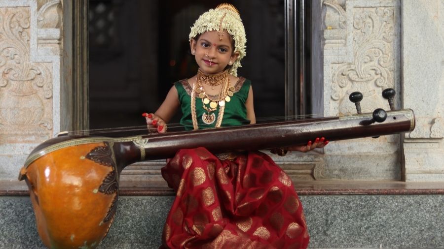 Indian girl holding traditional temple instrument