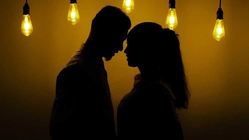 couple standing close in dark room with lights