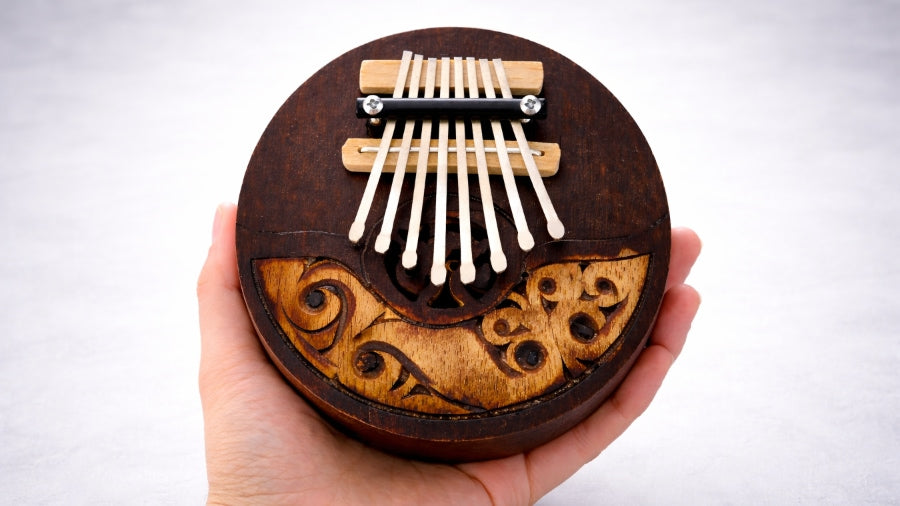 Coconut thumb piano held to show scale