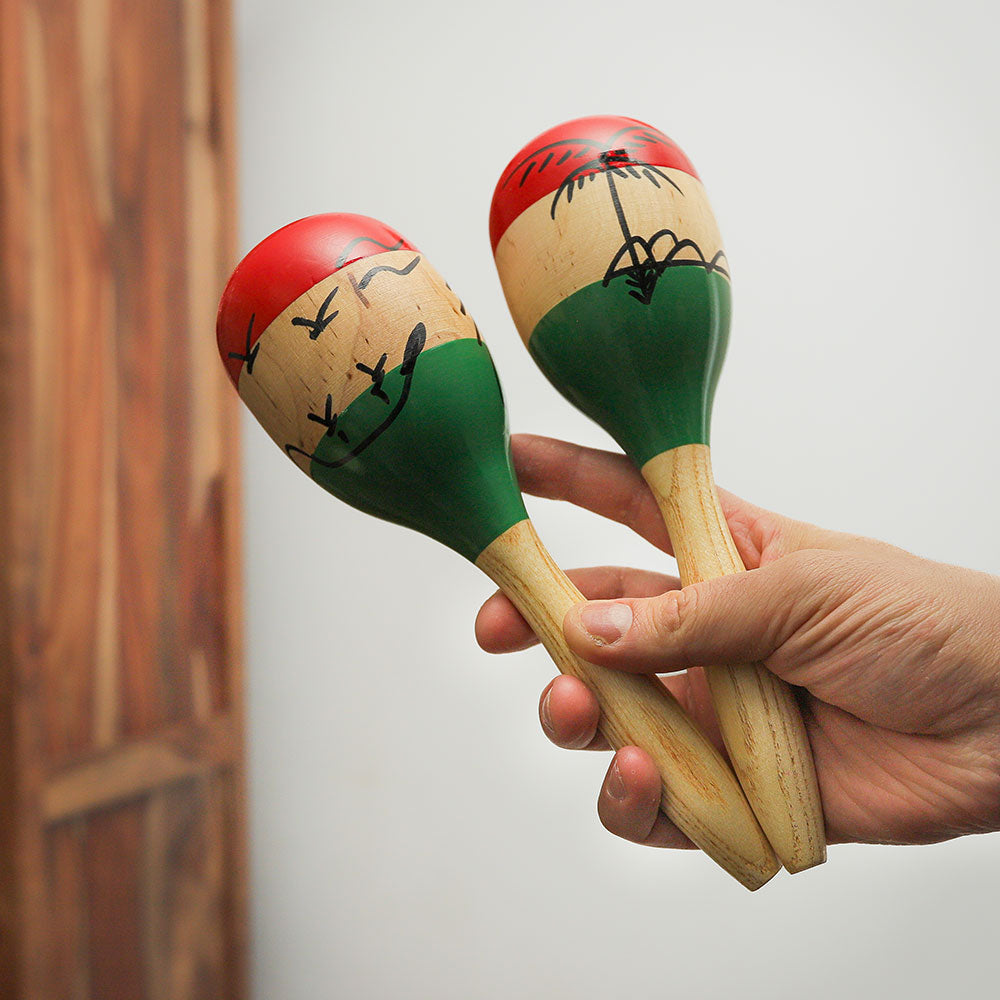 Handheld Agitar Maracas made from solid wood with iron beads inside. Features a vibrant Mexican-style design in red, white, and green.
