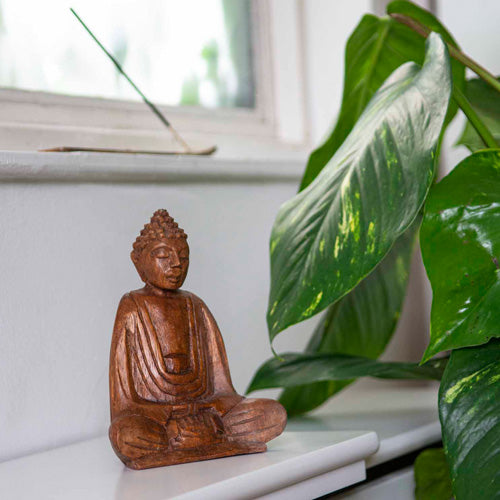 small 15cm sitting buddha on window seal with plant