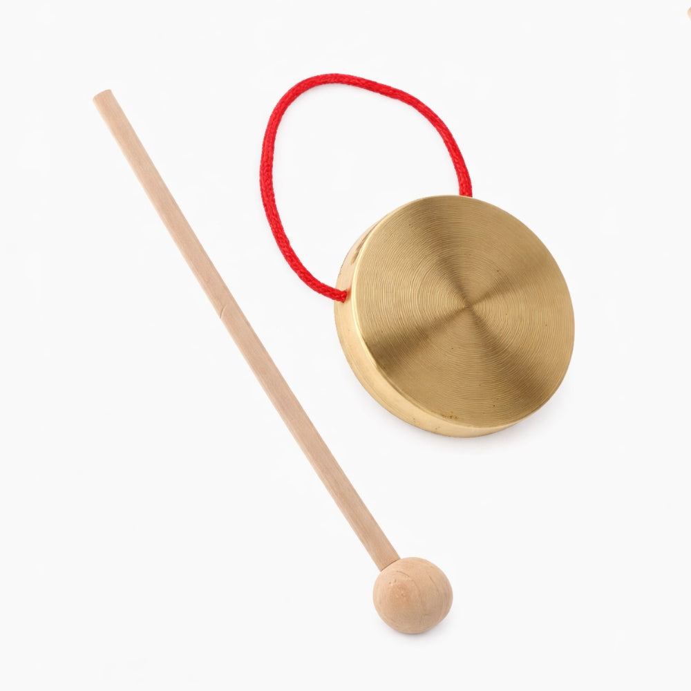 Small brass gong with red hanging loop and solid wood beater mallet on a white studio background