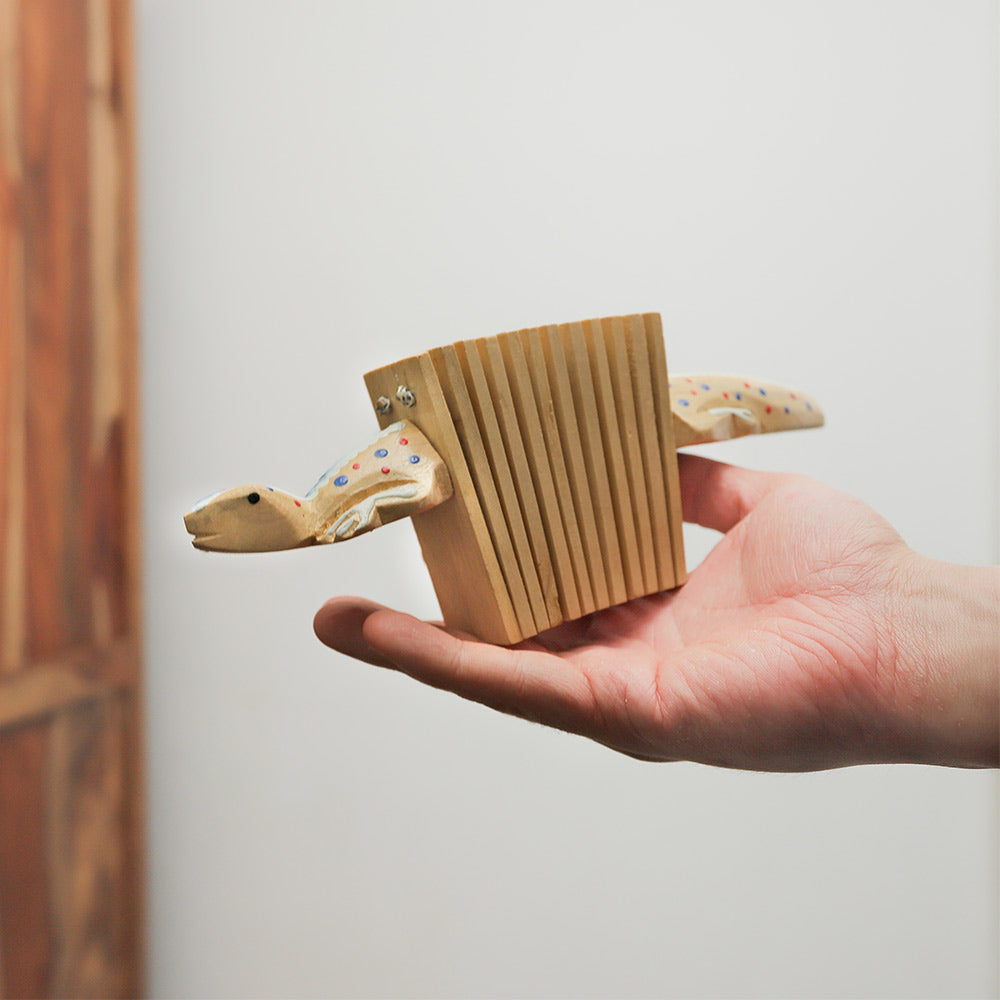 Gecko kokoriko percussion instrument held in hand, showing its size and gecko-shaped design.