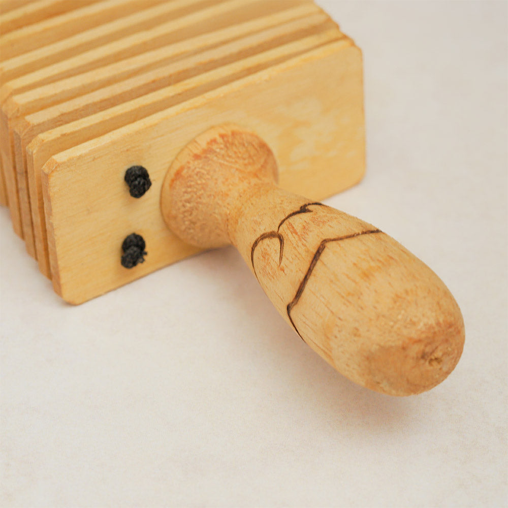 Close-up of the Indonesian wooden kokoriko handle, showcasing its detailed  texture.