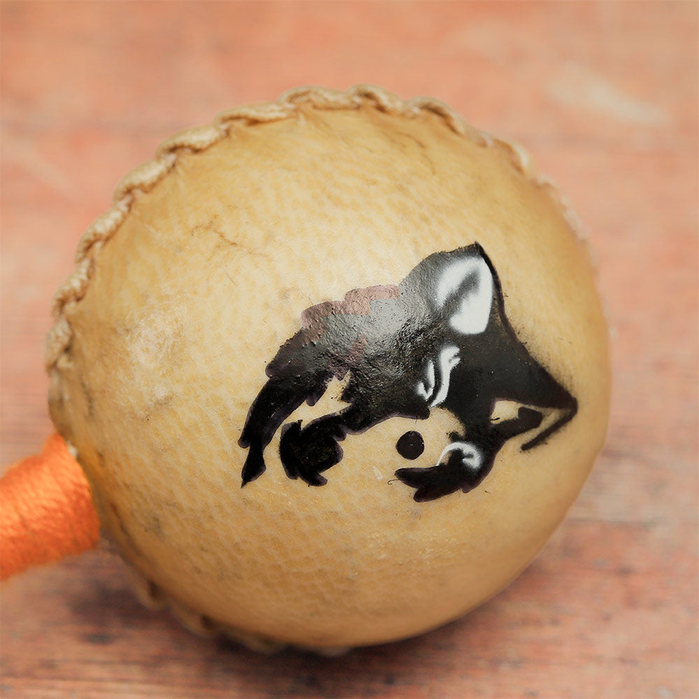 Close-up of the animal hide shaker head featuring a painted wolf face design.