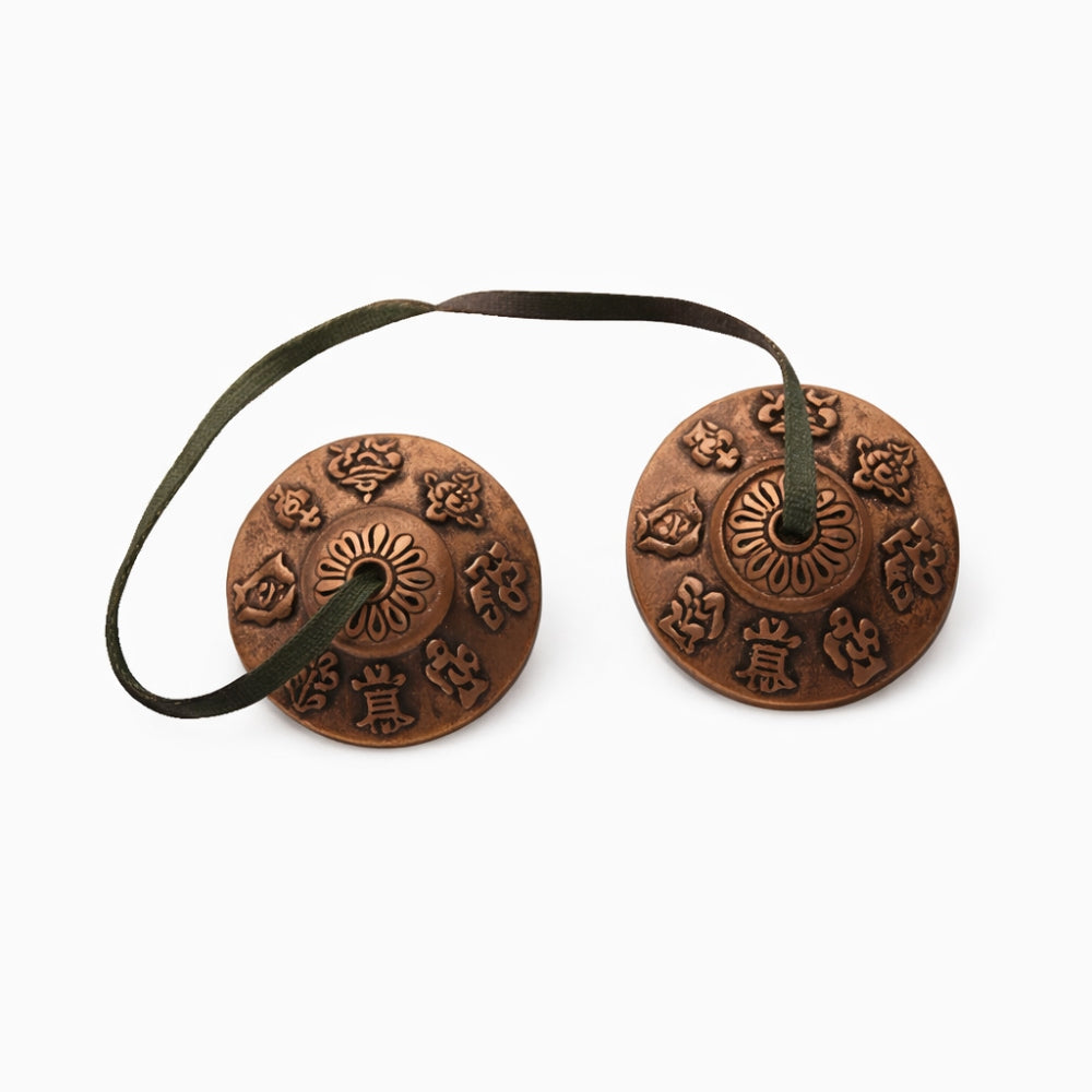 Close up of metal tibetan prayer bells with symbols showing  intricate designs on a white studio background