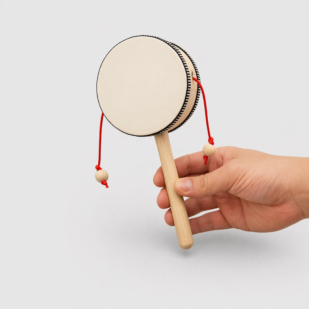 Hand holding a small wooden monkey drum with a white background