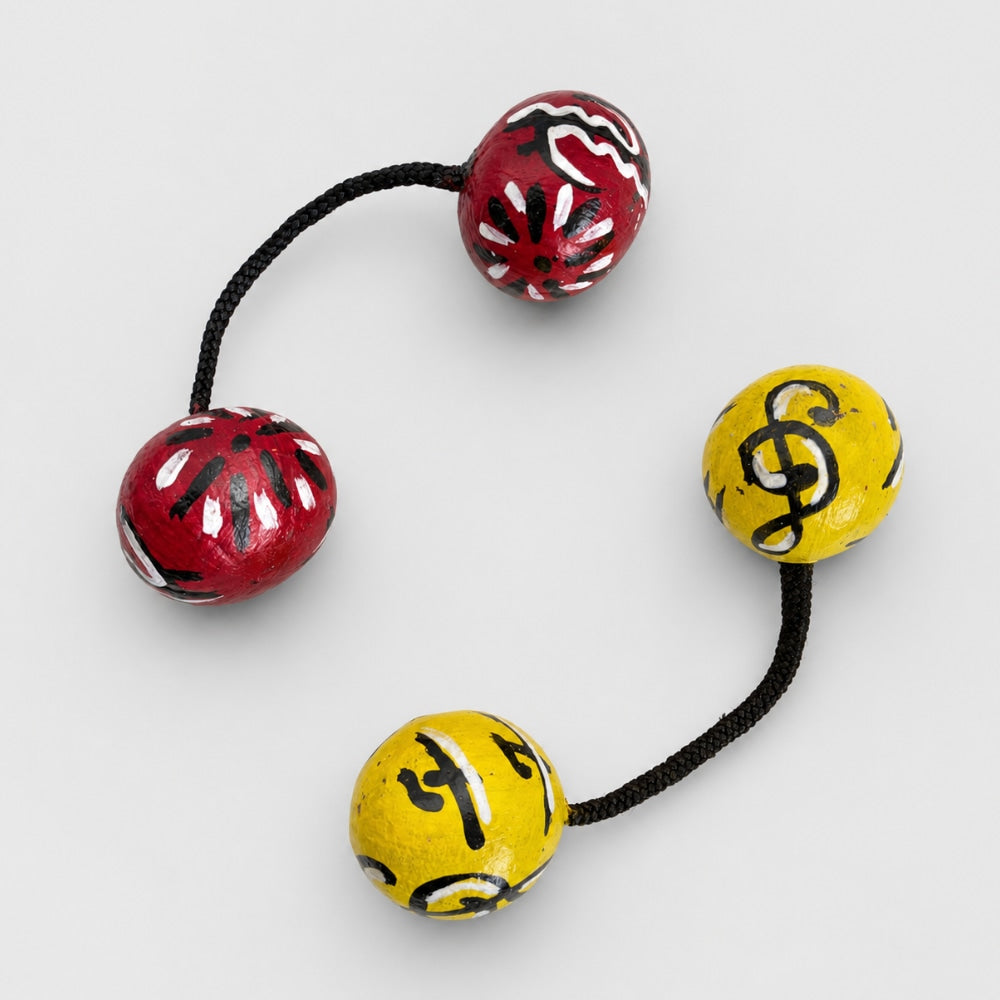 Pair of red and yellow african style kashaka shakers on a light grey studio background