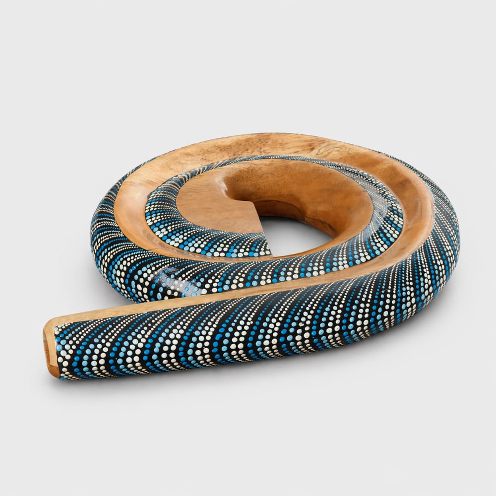 Indonesian spiral didgeridoo with blue dot painted design on a light grey studio background