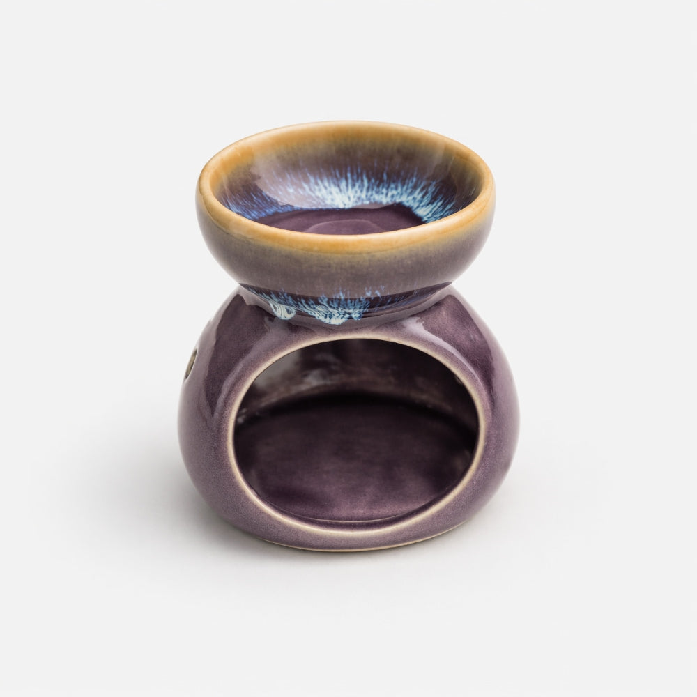 Close up of Purple ceramic oil burner with brown rim on a white background