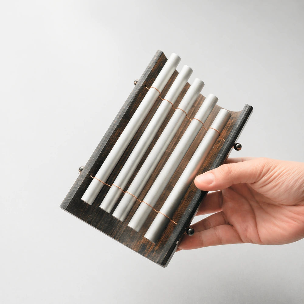 A Balinese Gamelan 5-note metallophone held in hand to demonstrate its size and portability.