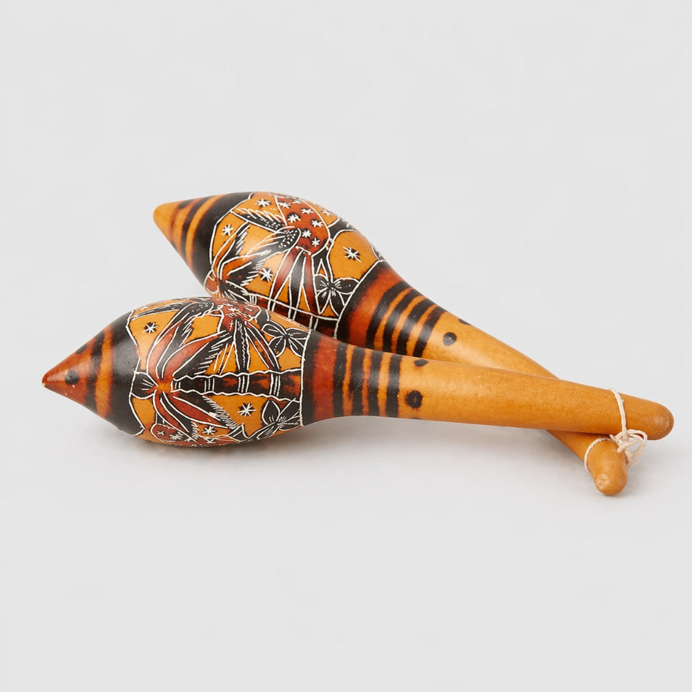 Pair of gourd maracas with decorative patterns on a light gray background