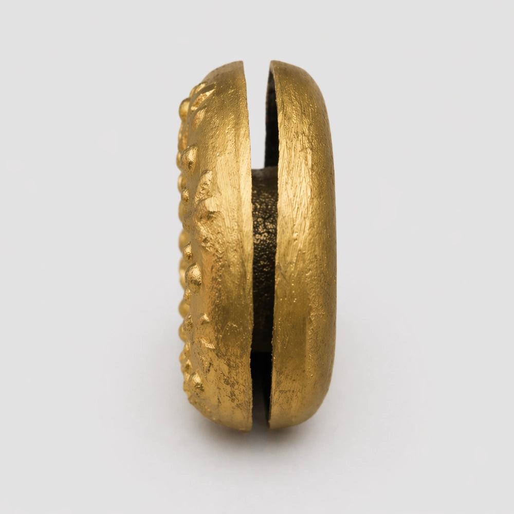 Side of the Brass Meo finger bell showing the slit in the middle, highlighting its construction.