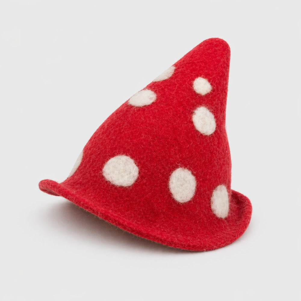Red mushroom-shaped felt wool hat with white spots on a light gray studio background